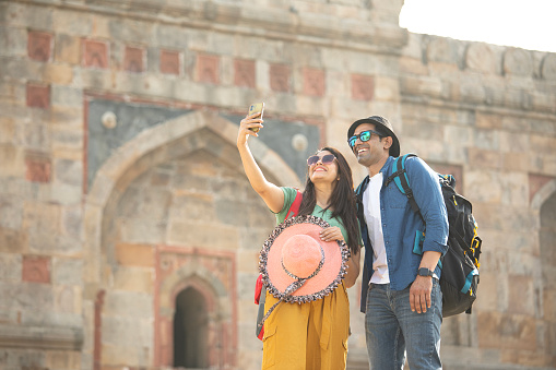 Happy couple taking selfie using mobile phone during vacation at historic site