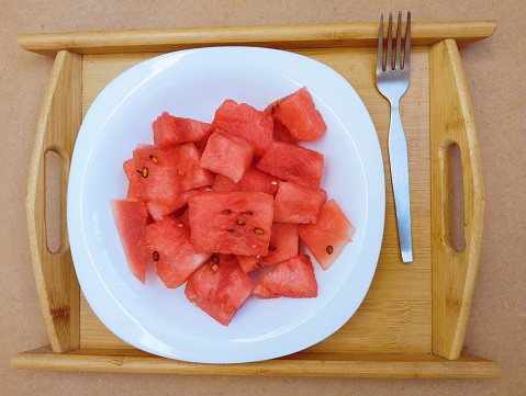 Sliced hybrid seedless watermelon with knife on a wood cutting board.