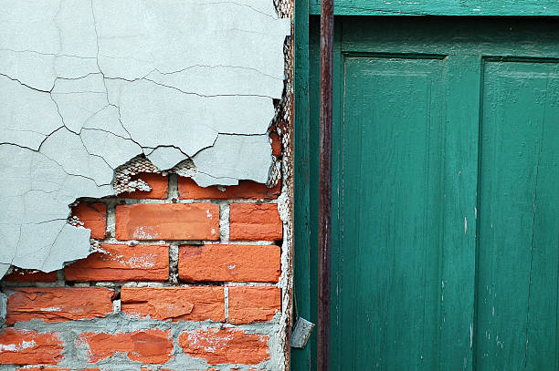 Cracked cement over exposed brick with green door stock photo