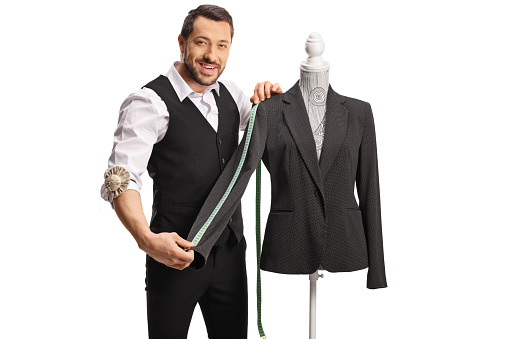 Tailor measuring a sleeve from a suit on a mannequin torso isolated on white background