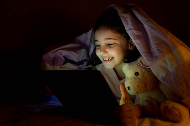 istock Little girl using digital tablet in her bed at night 1476704037