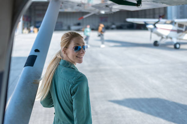Travel and aviation concept. Elegant woman near aircraft, engine, and jet on the runway. Air travel, technology, and aerospace.