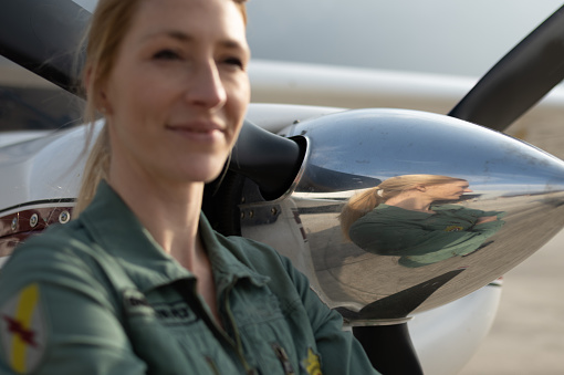 A female pilot with pilot sun glasses prepares to fly her sport plane. She enjoys the feeling of freedom, the wind in his hair on the wings of the plane.
