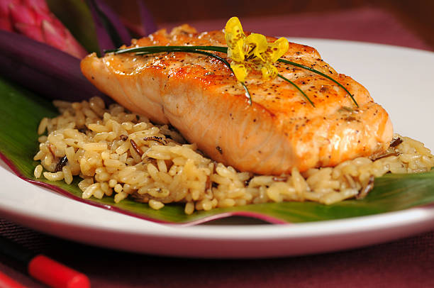 Salmon fillet served over a bed of rice on a banana leaf stock photo