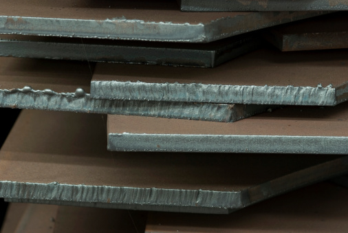 Close-up of stack of steel plates cut to different shapes.