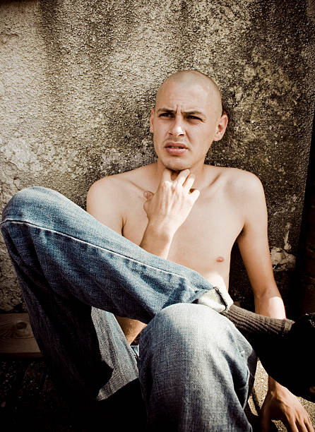 Skinhead picture of a young man leaning against wall skinhead haircut stock pictures, royalty-free photos & images