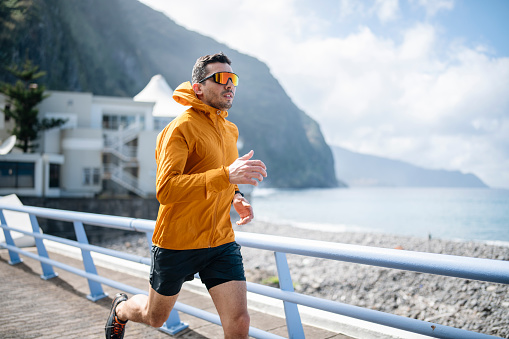 Man enjoying his regular running session on a bridge by the ocean.