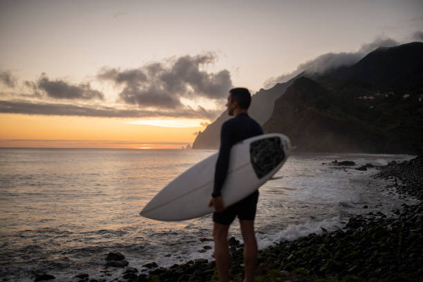 istock Surfer with surfboard looking at the ocean at dawn. 1476709803