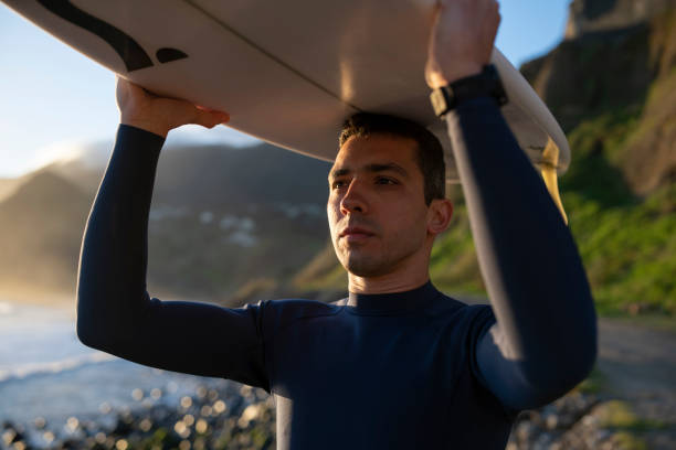 istock Surfer holding his board over his head and going in the ocean. 1476709811