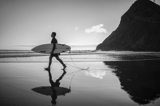 Black and white photo of professional surfer by the ocean.