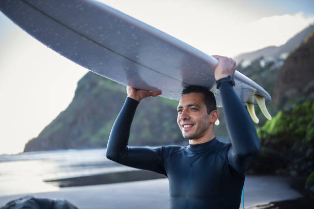 istock Surfer holding his board over his head and going in the ocean. 1476709851