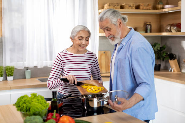 healthy nutrition. happy senior couple preparing vegetable meal together in kitchen - two parent family indoors home interior domestic kitchen imagens e fotografias de stock