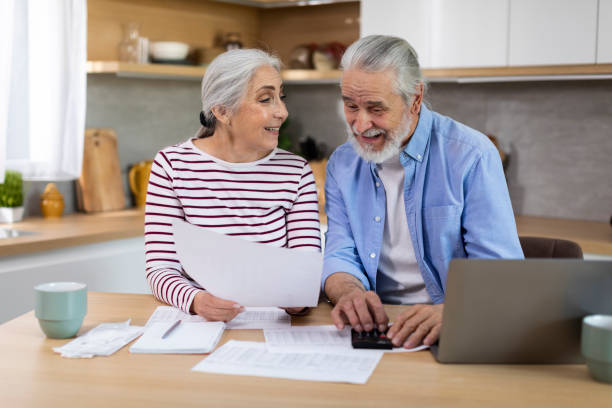 portrait of cheerful elderly spouses sitting in kitchen and checking financial papers - two parent family indoors home interior domestic kitchen imagens e fotografias de stock