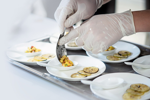 Focused hand male chef in  uniform decorate food, garnishes, prepare dish , in white plate in kitchen.