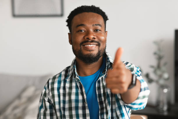 istock Black Male Gesturing Thumbs Up In Approval Posing At Home 1476710267