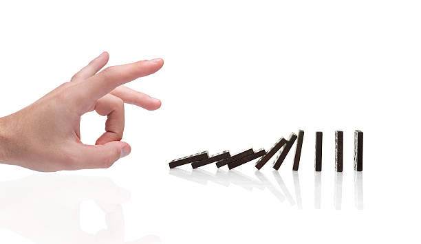 istock Fingers knocking over black dominoes 147671134