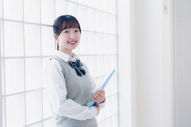A high school girl walking around the school with teaching materials stock photo