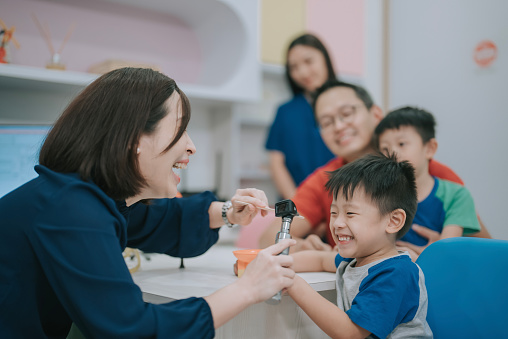 Asian Chinese female Paediatrician examining young boy in her clinic