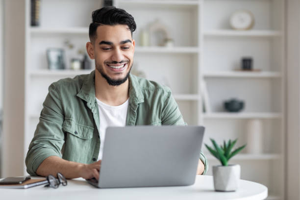 istock Young arab male writer working on laptop computer at home office 1476719508