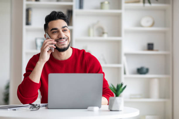istock Handsome Young Middle Eastern Male Talking On Mobile Phone At Home Office 1476719703