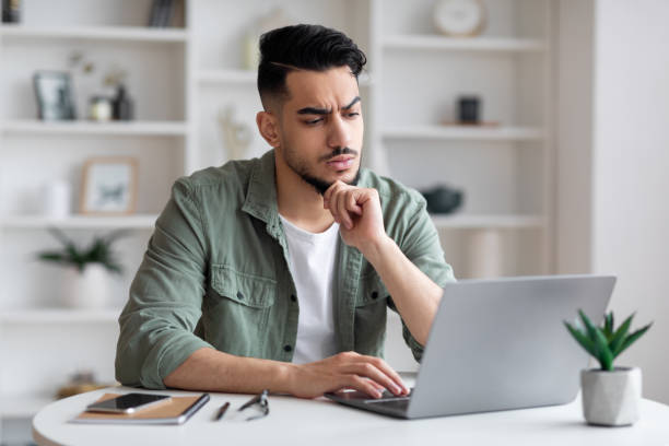 istock Thoughtful concentrated sad young arabic man with beard typing on laptop and have problem with job 1476719721