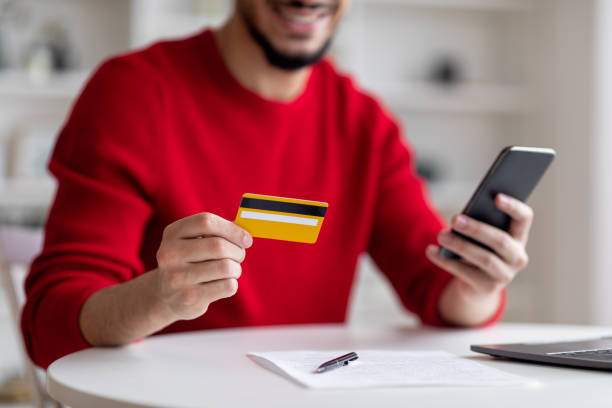 istock Paying Bills Online. Arab man using smartphone and credit card at home 1476720886