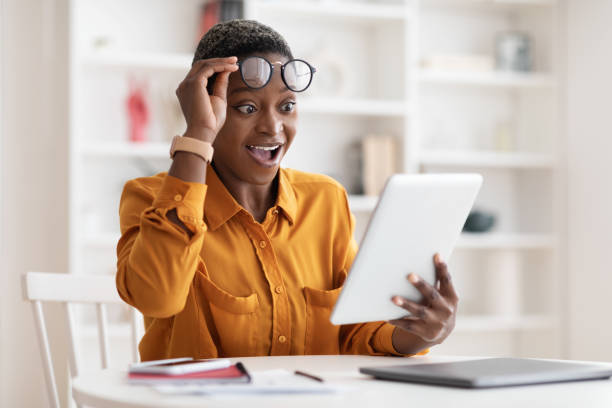 사무실에서 디지털 태블릿을 사용하는 놀란 흑인 여성 - digital tablet blog women reading 뉴스 사진 ��이미지