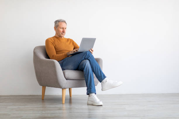 istock Confident mature man using laptop sitting on chair 1476721356