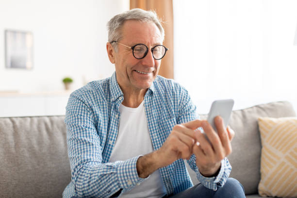 istock Portrait of mature man using smartphone sitting on couch 1476722131