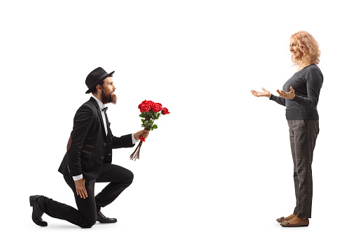 Man kneeling and giving a red roses to a happy woman isolated on white background