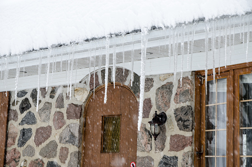 Icicle melting from house rooftop and hanging from gutter