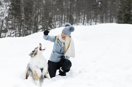 The girl plays with her white dog in the snow and rests.