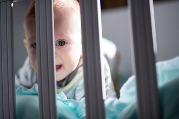 istock Charming baby boy peeking through his crib. 1476724285