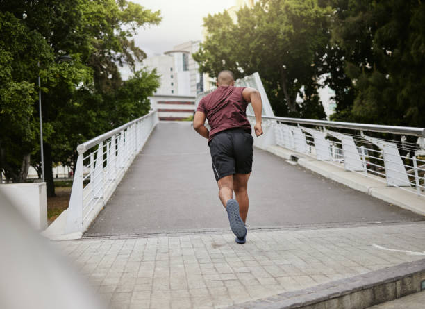 フィットネス、運動、または健康、有酸素運動、またはトレーニングのために都市、通り、または道路の橋の上を走る黒人男性。健康目標、マラソン、またはレースイベントのためのニュー� - marathon sport sports training city street ストックフォトと画像