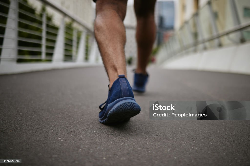 Fitness, legs or runner walking on a city bridge in a warm for training, cardio exercise or calf muscle workout. Wellness, zoom or sports athlete trekking or exercising with running shoes or footwear Walking Stock Photo