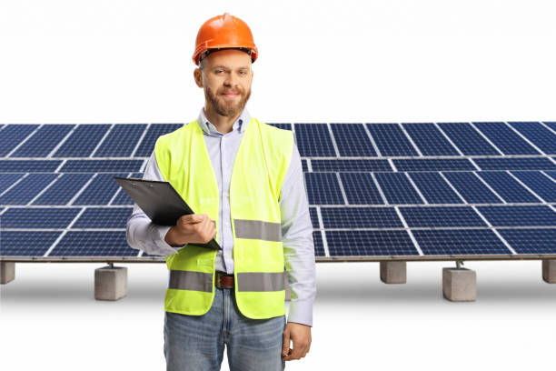istock Young male engineer with a hardhat holding a clipboard in front of solar panels 1476725619