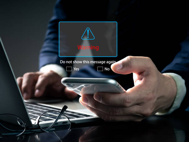 istock phishing email warning pop-ups, spam email, and network security concept blocking. A businessman sees a warning popup while working on his laptop at home 1476727513