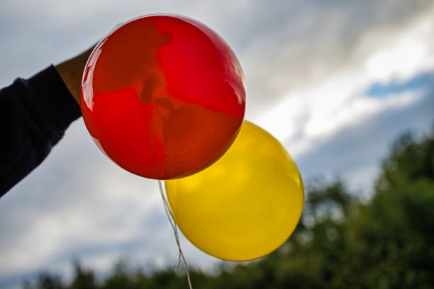 istock Hand holding red, yellow balloon 1476727820