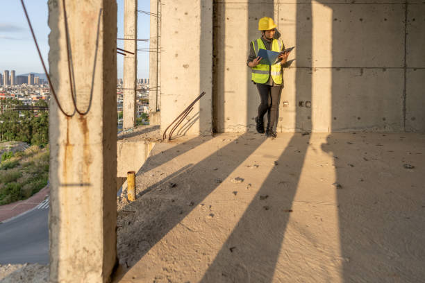 istock A female construction worker is holding blueprints and working on a construction site with sunlight 1476730012