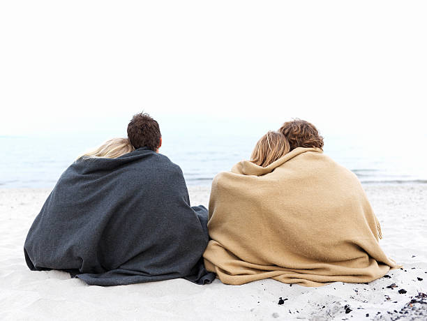 istock Couples sitting together on the beach in winter 147673083