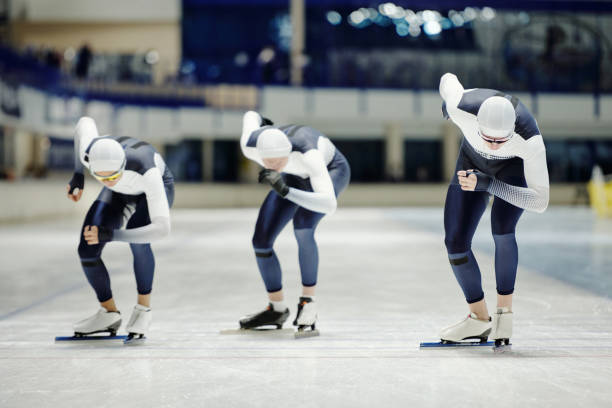 istock Three young male ice skaters sliding along rink on arena 1476731796