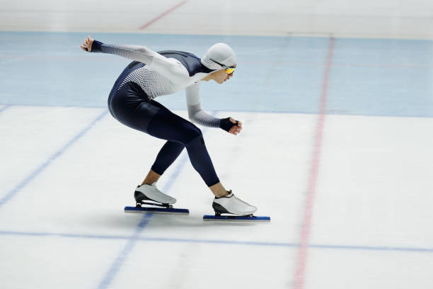 istock Speed skater bending forwards over ice rink while moving along arena 1476731899