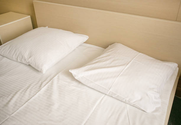 istock Close-up of white sheets and pillow in a hotel room, modern interior 1476732073