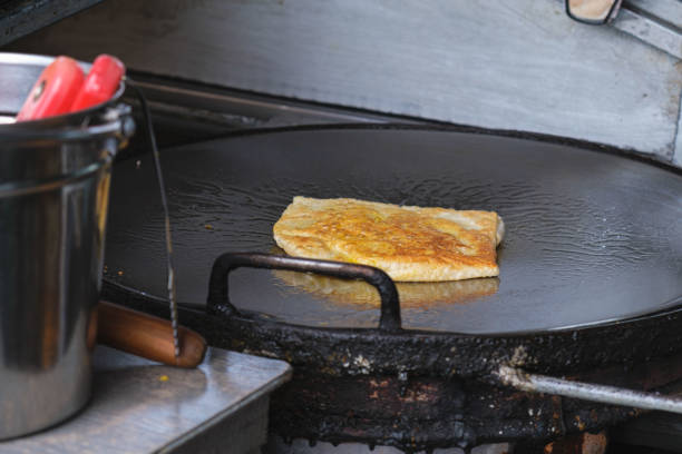 Traditional Thai stuffed pancake is fried in a hot frying pan. Asian street food. Street food and Thai desserts. Making Roti on the Pan for Snacks