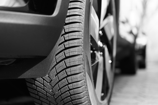 Summer car tires on over blue sky with clouds. Tire stack background. Car tyre protector close up. Black rubber tire. Brand new car tires. Close up black tyre profile. Car tires in a row