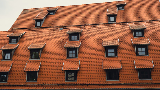 Corner with dormers Red Roofs of the city brown metal tiles roof of European house with windows. Typical European old brick roof with windows. Bydgoszcz city