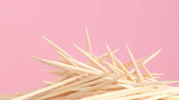 Photo of Close-up of a group of wooden toothpicks on a pink background.