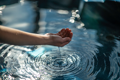 Hydromassage. Woman relaxing in crystal clear bubbling hot tub reflecting sunlight.