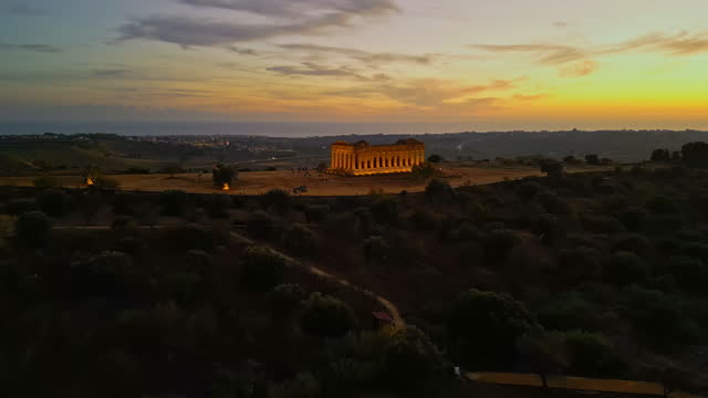 Drone shot of illuminated Temple of Concordia amidst landscape at sunset