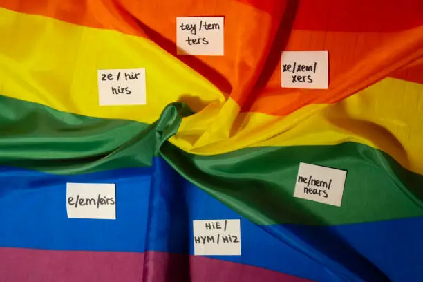 Neo pronouns concept. Rainbow flag with paper notes text gender pronouns hie, e, ne, xe, ze, tey. Non-binary people rights transgenders. Lgbtq community support assume my gender, respect pronouns tolerance equal rights